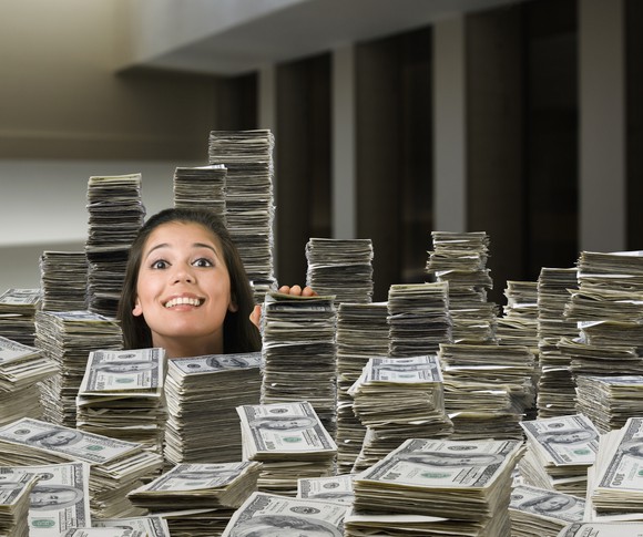 A lady buried in stacks of cash peeking out.