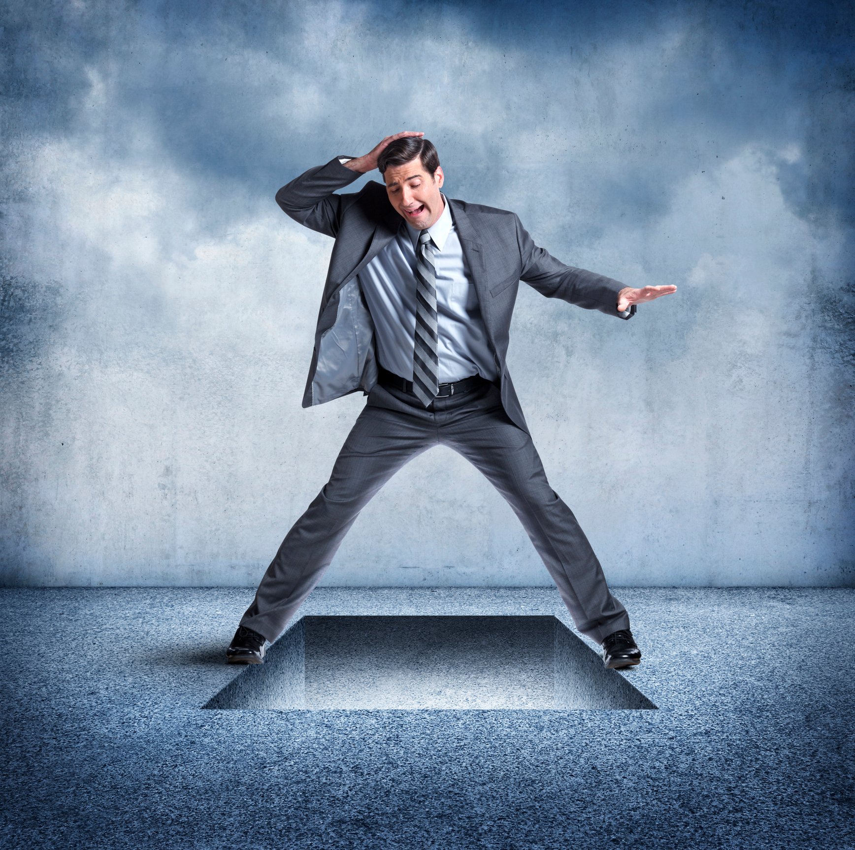 A businessman standing over a trap door