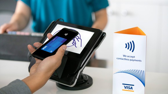 A person using credit card info stored on their smartphone at a contactless point-of-sale system. 