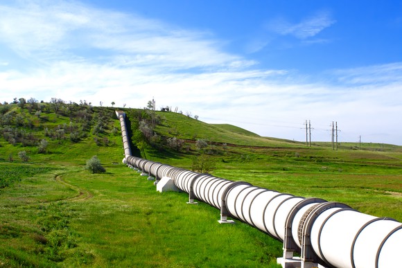 An oil pipeline on green grass under blue sky. 