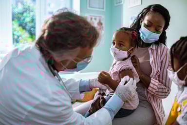 little girl receives vaccine from male doctor