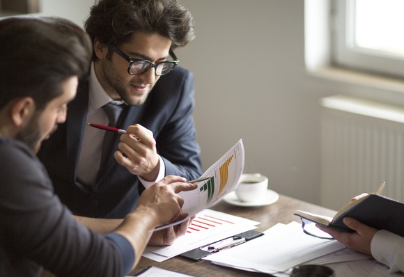 Two businesspeople examine printouts.