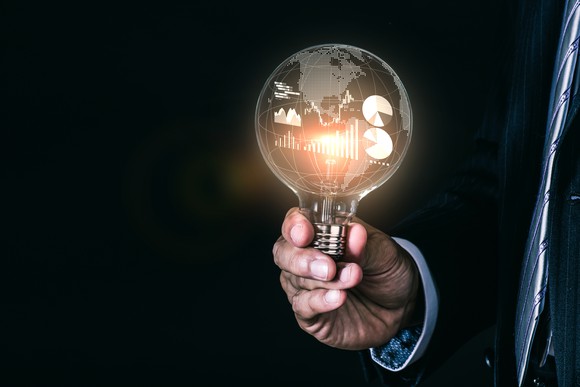 A person holding a lightbulb with charts and graphs inside.