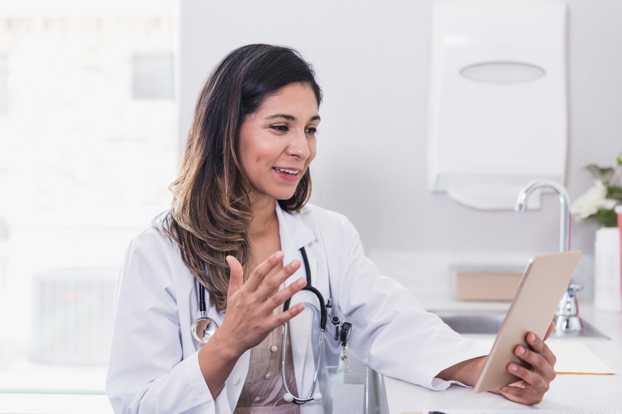 Doctor speaking with someone via tablet.