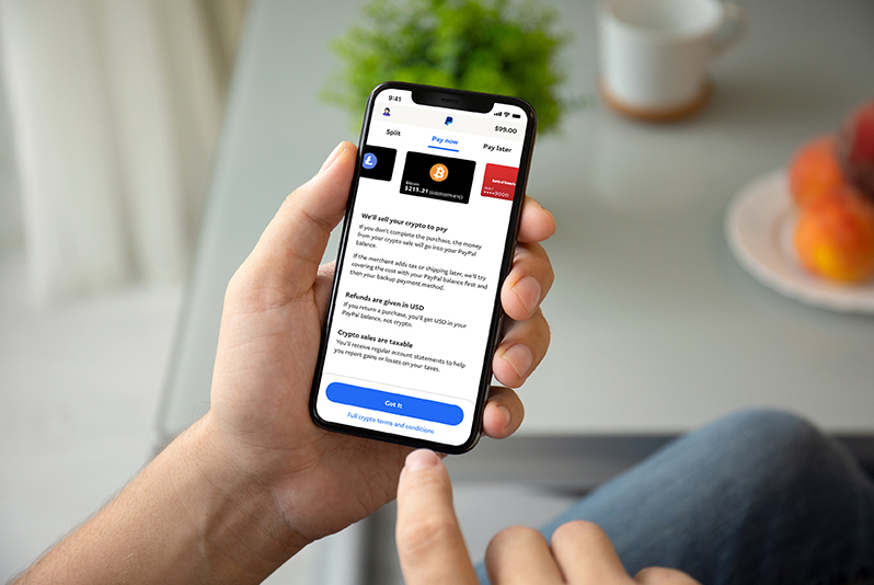 A person holding a smartphone with an app displaying cryptocurrency payment options.