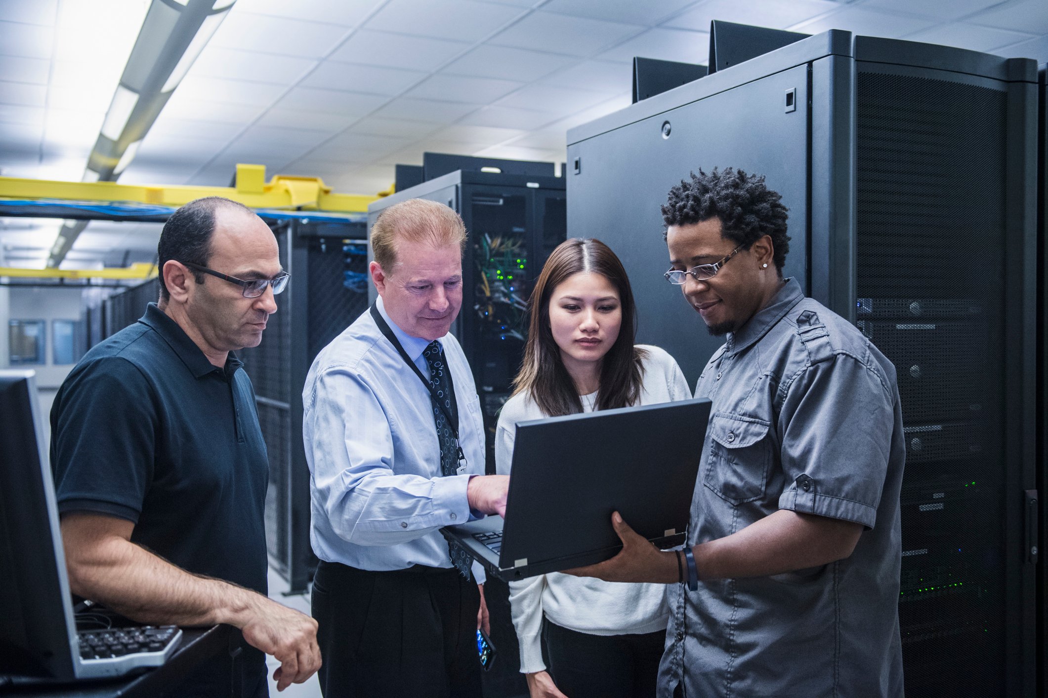 Colleagues looking at laptop in a data center.