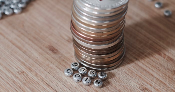 Stacks of coins with metal beads spelling out the word "Dogecoin".