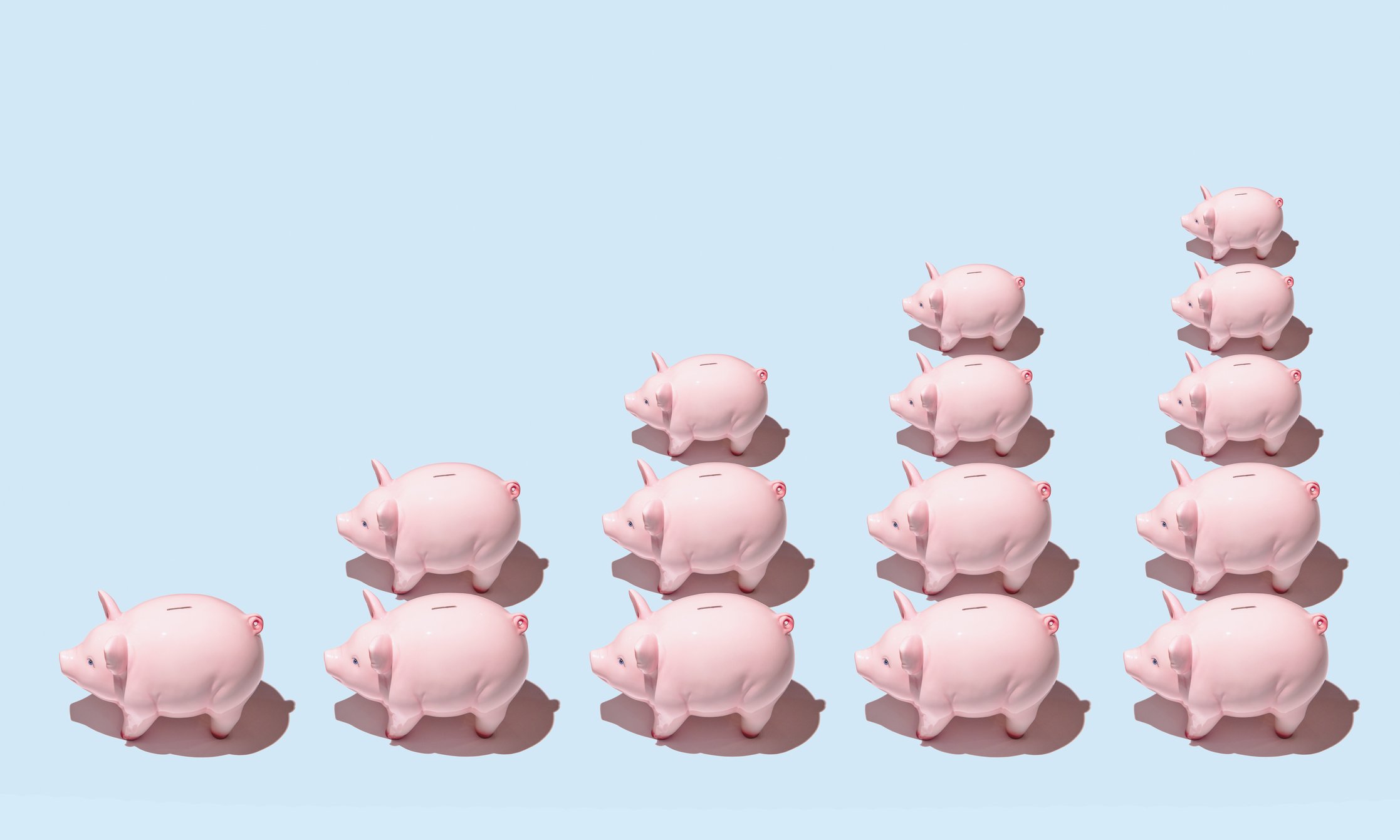Piggy banks lined up in stacks of increasing height.