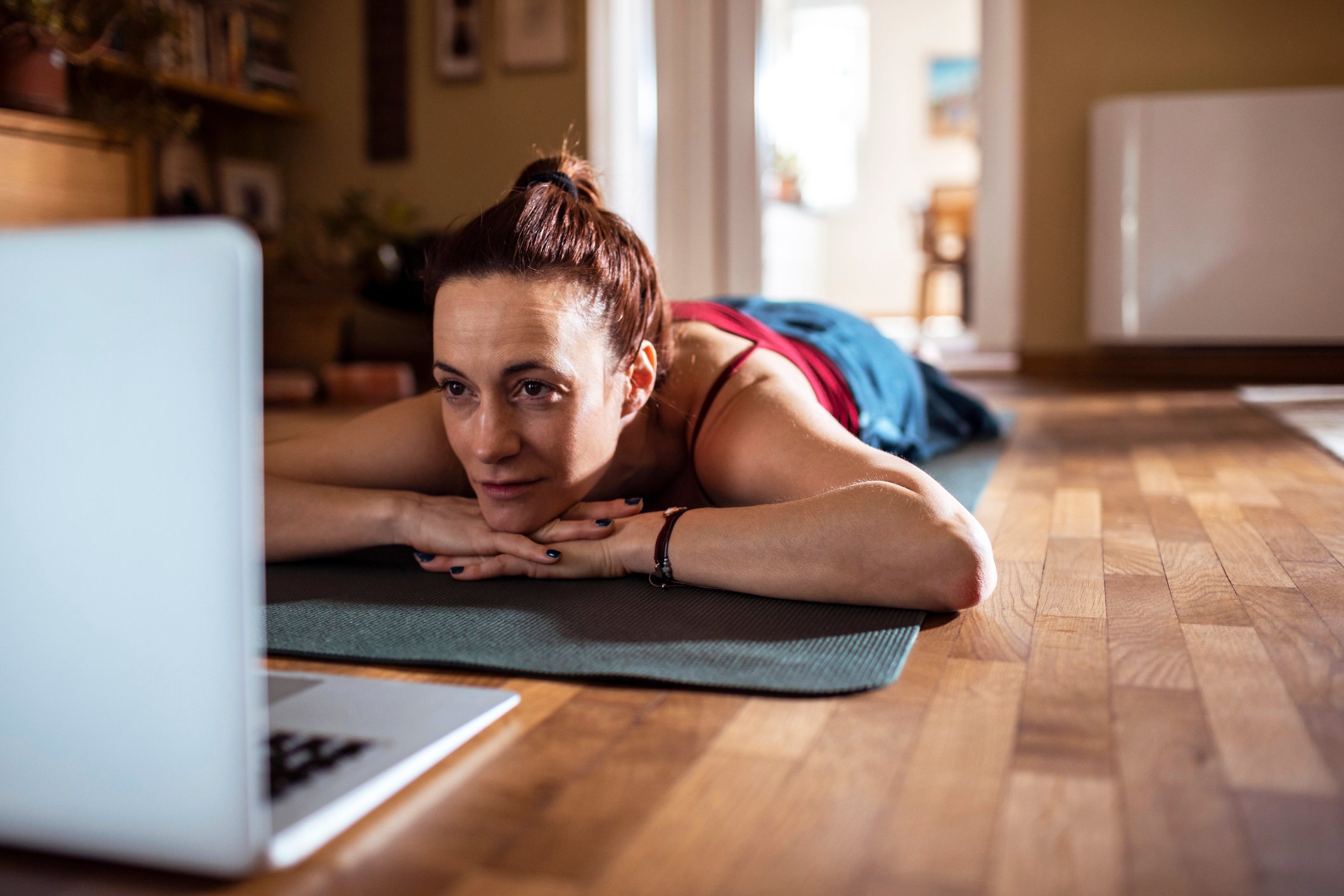 Young woman using a laptop while doing yoga.