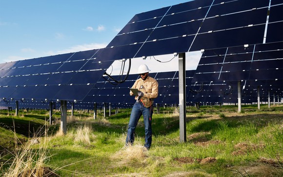 Worker standing in front of solar panels