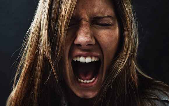 A panicked woman screams against a black background.