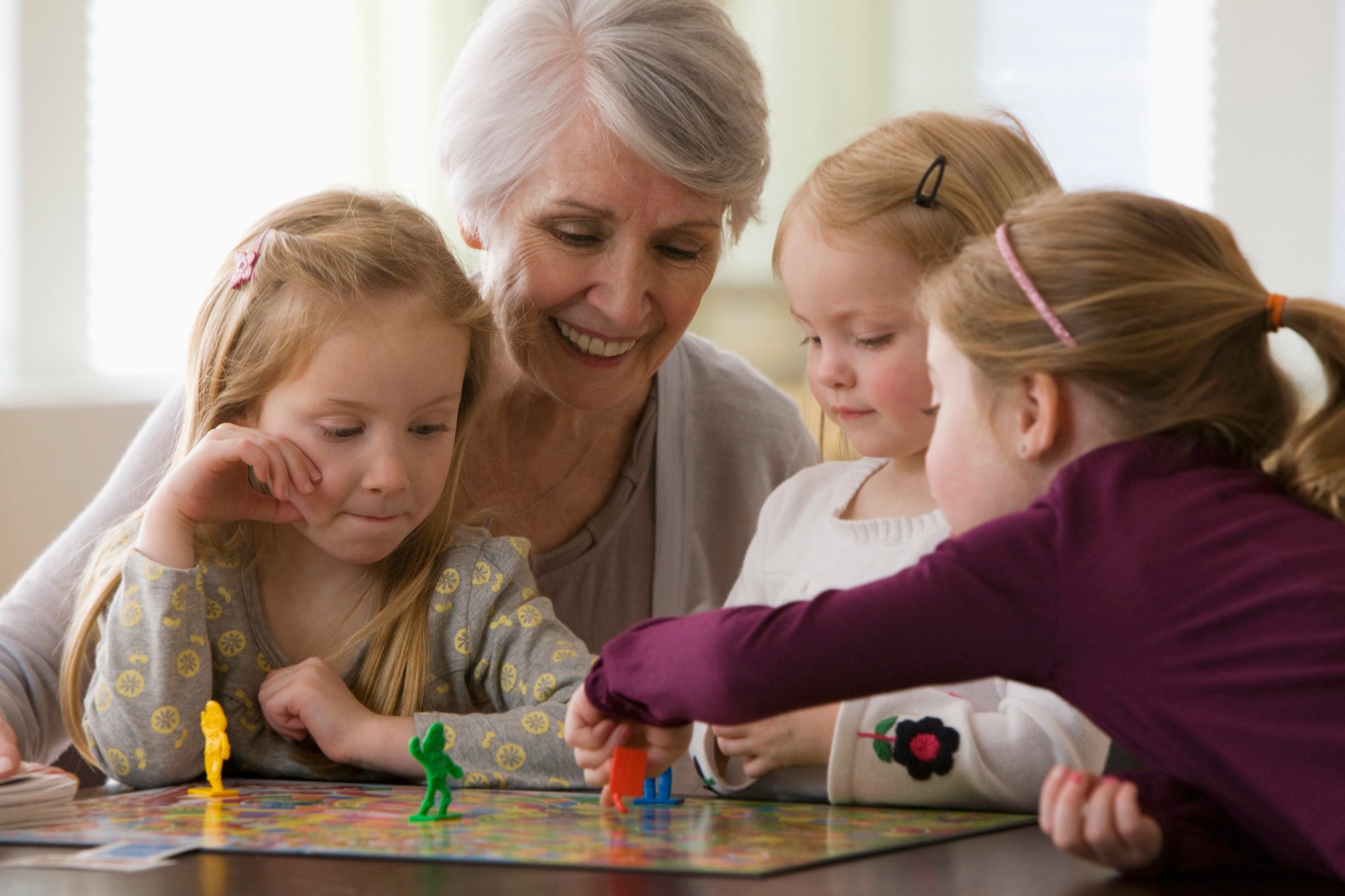 A woman playing a board game with her grandchildren.