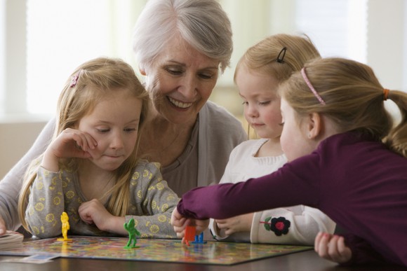 A woman playing a board game with her grandchildren.