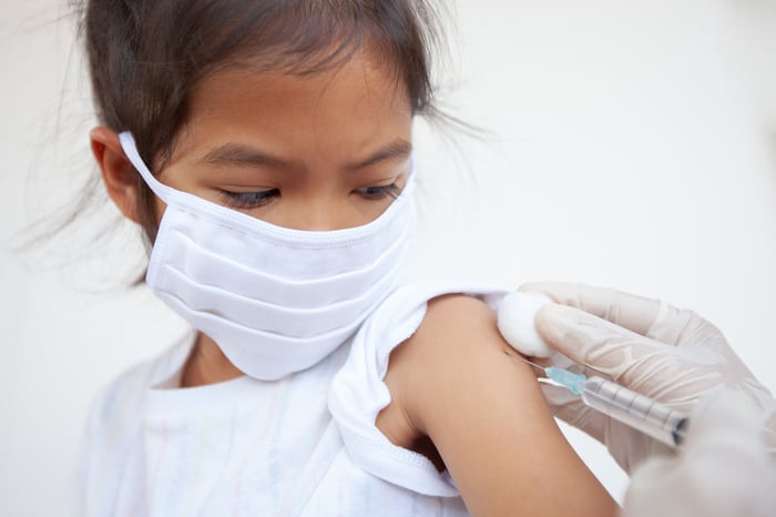 Child getting a syringe jab from a medical professional.