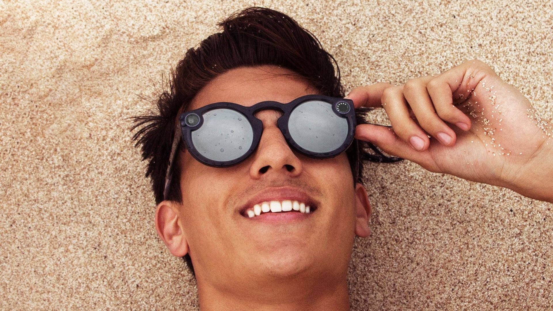 A man wears a pair of Snapchat Spectacles at the beach.