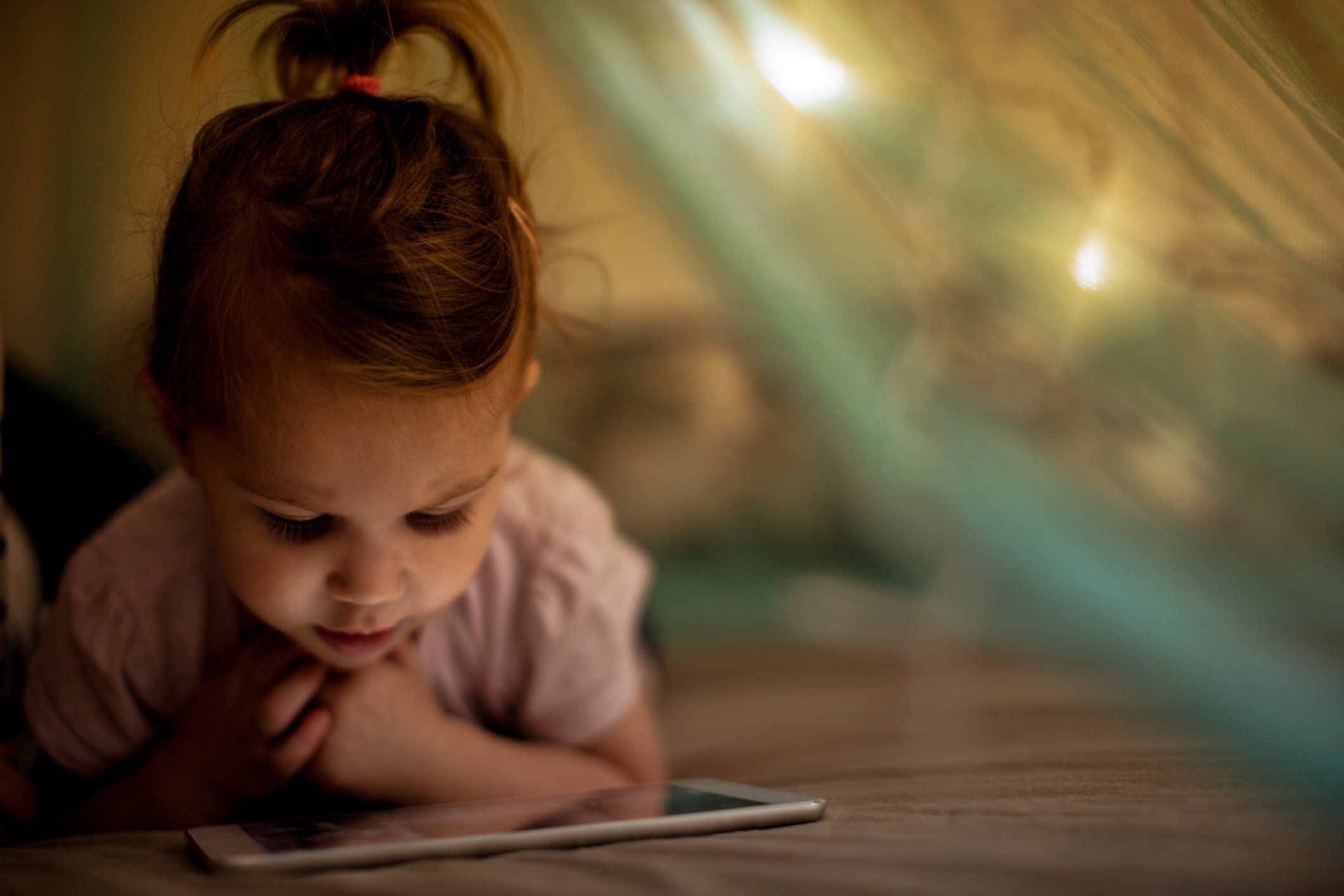 A young girl looking at a tablet.