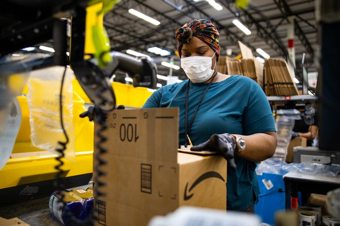 A worker in an Amazon fulfillment center tapes a box.