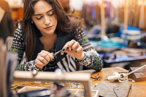 Young woman crafting jewelry in a workshop.