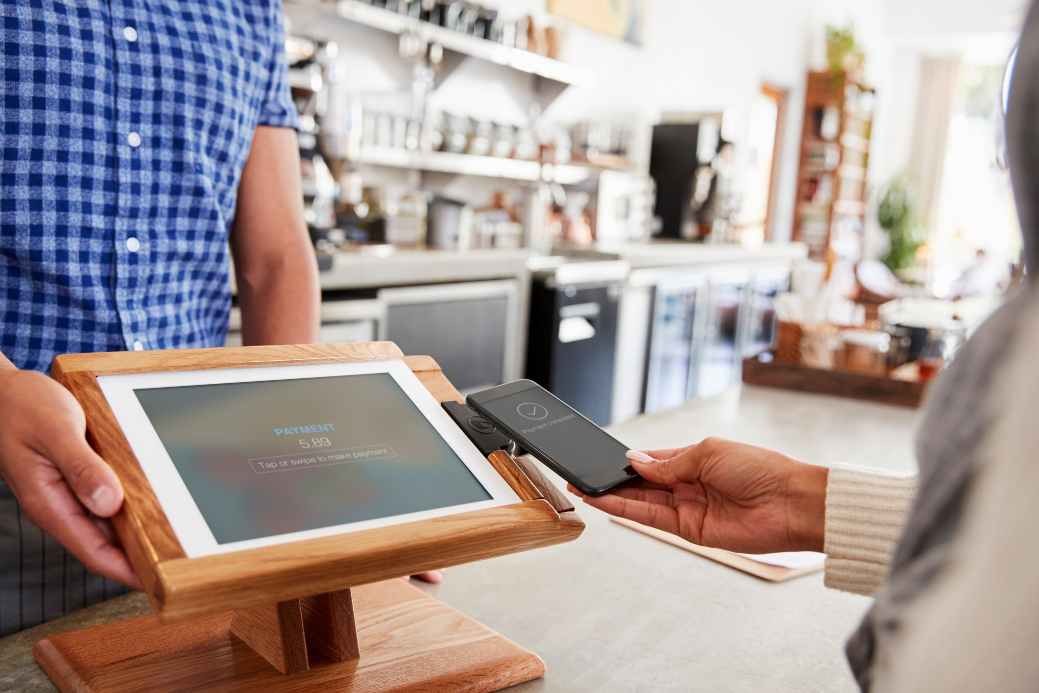 Woman making payment by smartphone at coffee shop. 
