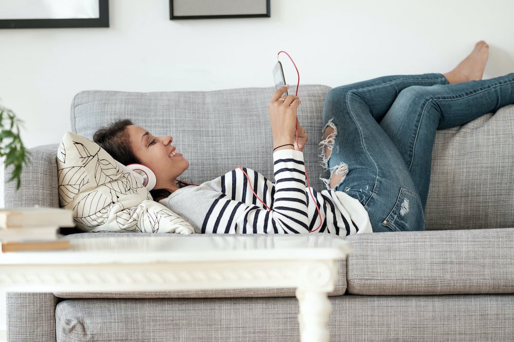 A woman lying on the couch watching something on her phone