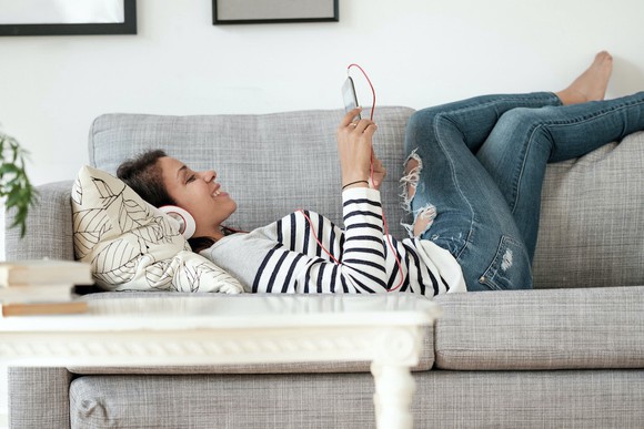 A woman lying on the couch watching something on her phone
