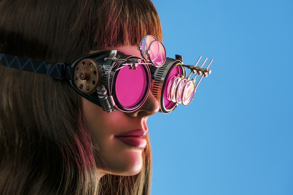 A woman wears a pair of futuristic steampunk glasses.