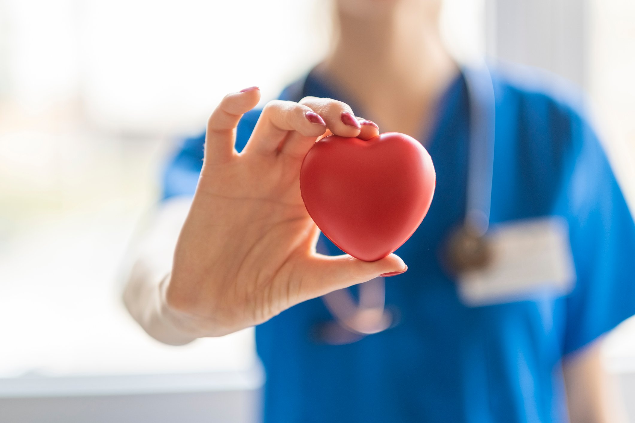 A doctor holds a heart symbol.