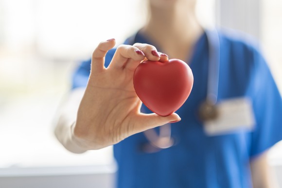 A doctor holds a heart symbol.