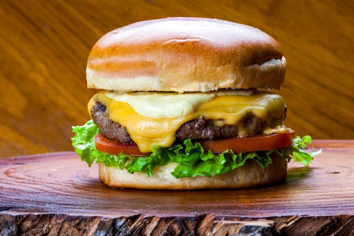 A cheeseburger sitting on a wooden board.