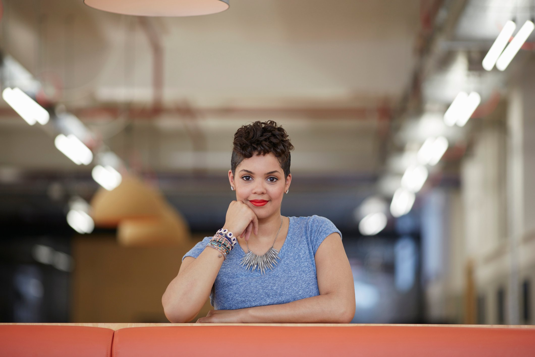 Woman at desk, fist holding up her chin, looking ahead as if waiting for an answer