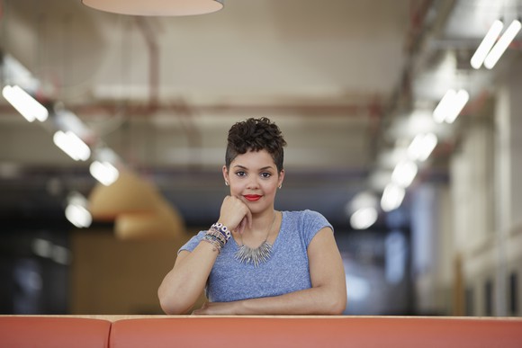 Woman at desk, fist holding up her chin, looking ahead as if waiting for an answer