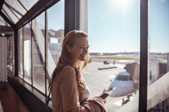 A woman looks out the window at an airport.