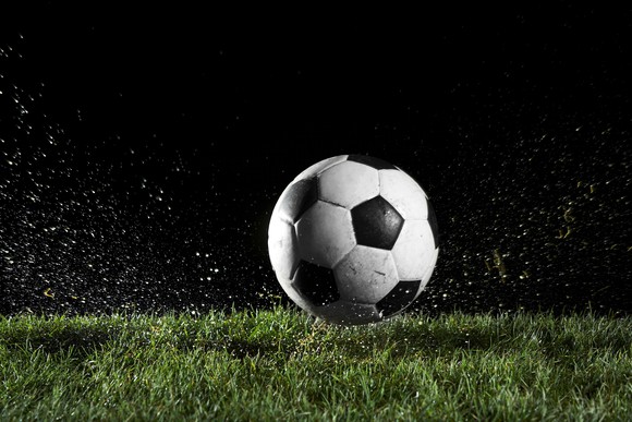 A soccer ball on wet grass at night.