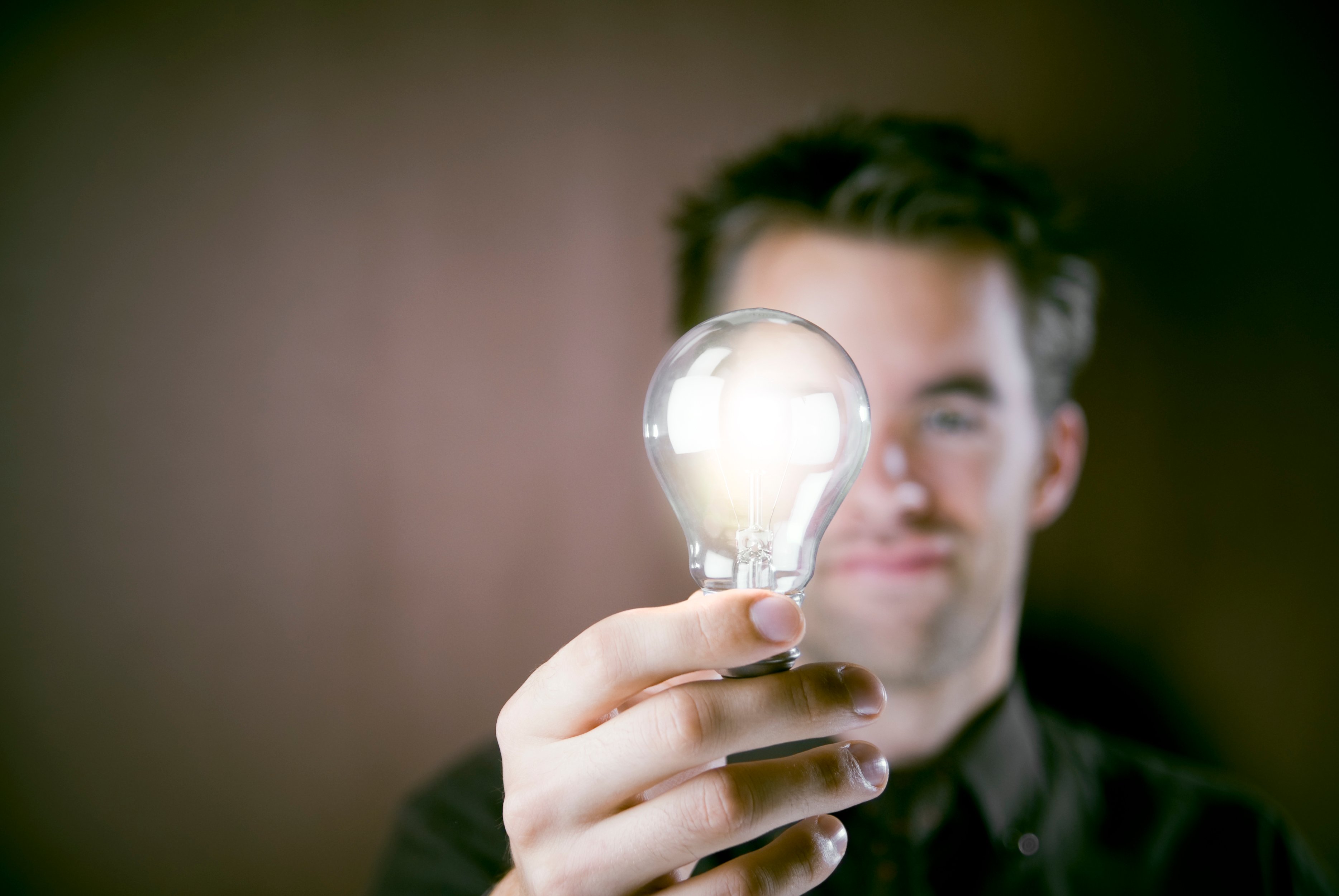 Man holding a lit lightbulb  