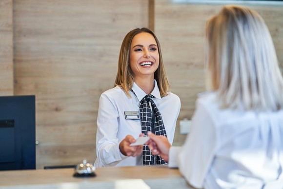 A front desk clerk at a hotel checking in a guest. 