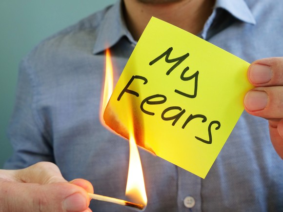 Someone lighting on fire a sticky note that reads "my fears"