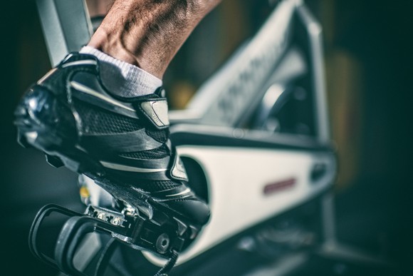 A foot on a pedal of an exercise bike. 