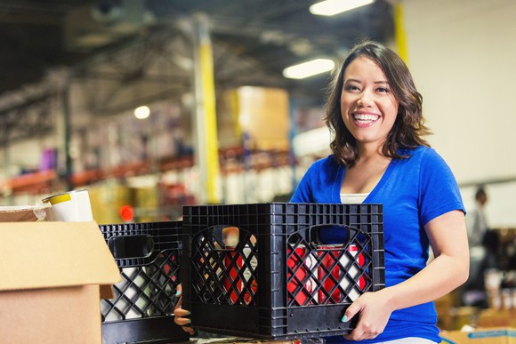 A woman holing a crate in a warehouse.