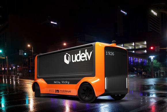 A Udelv Transporter, an orange and black self-driving van. 