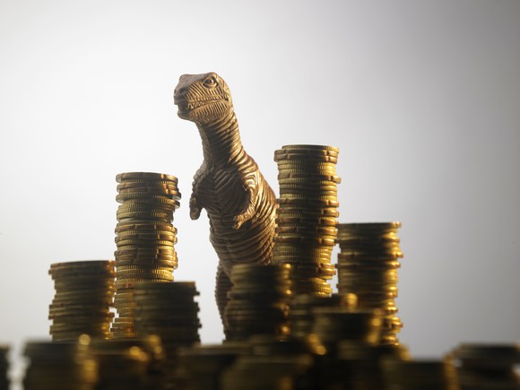 a toy dinosaur is positioned between multiple stacks of coins