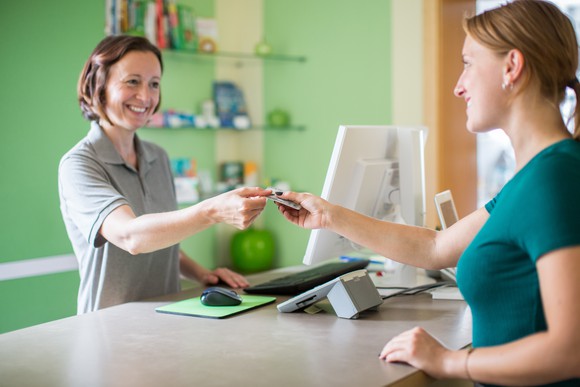 Woman presenting health insurance card to clinic. 