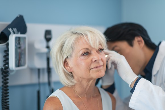 A doctor checks a woman's ear.