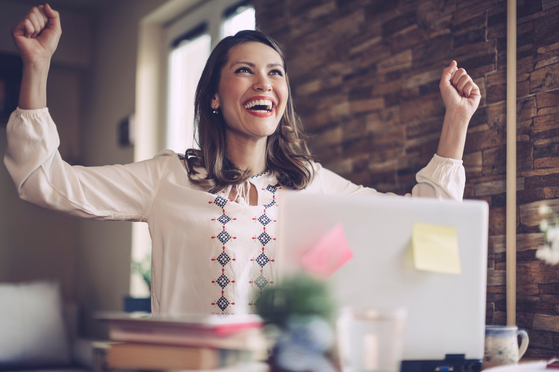 Woman cheering in front of laptop