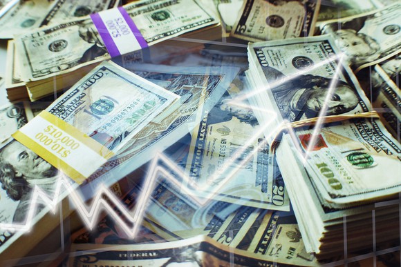 An upward rising arrow superimposed over bundles of cash.