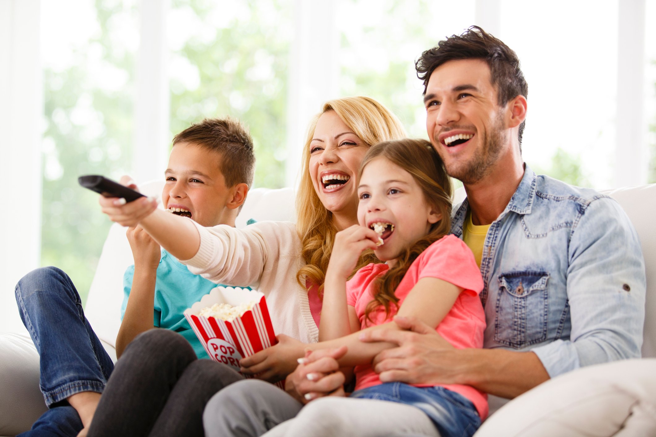 A family watching TV while sitting on a couch.