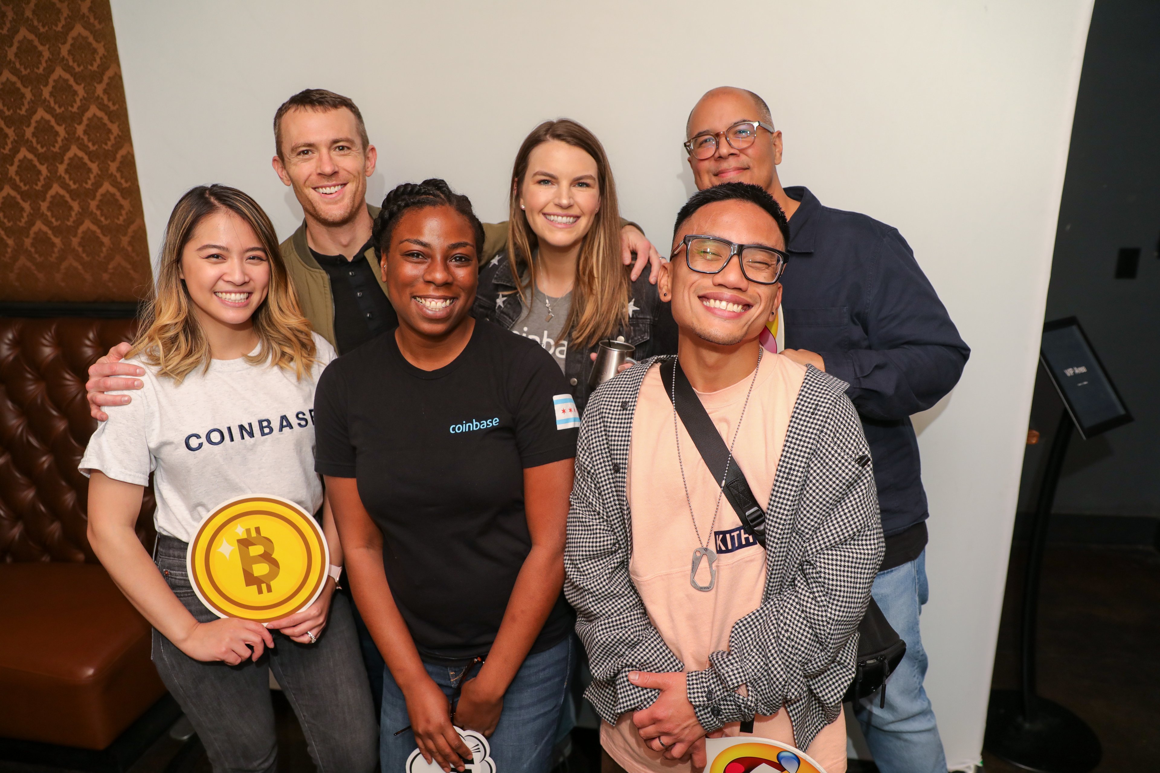 group of coinbase employees with one holding a bitcoin symbol