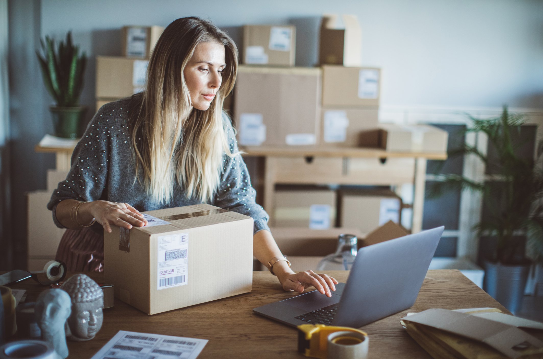 Woman using her laptop as she prepares to send an order from her business.