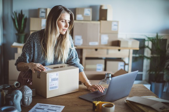 Woman using her laptop as she prepares to send an order from her business.