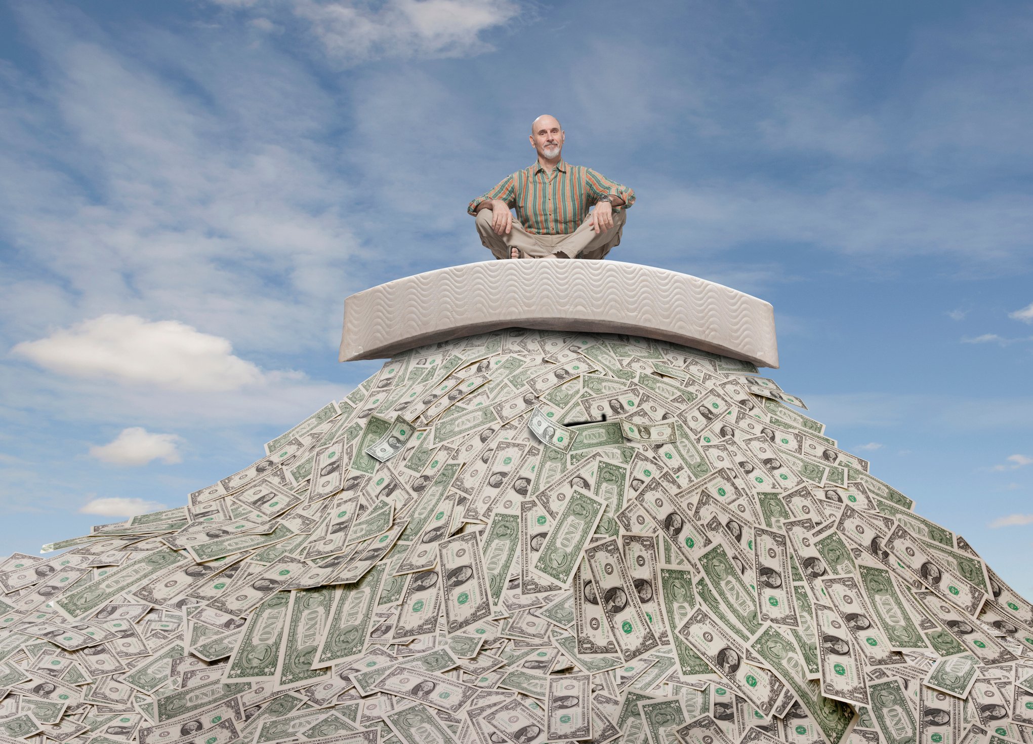 Senior sitting atop pile of money