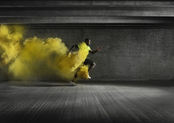 A runner sprinting with yellow smoke in his wake.